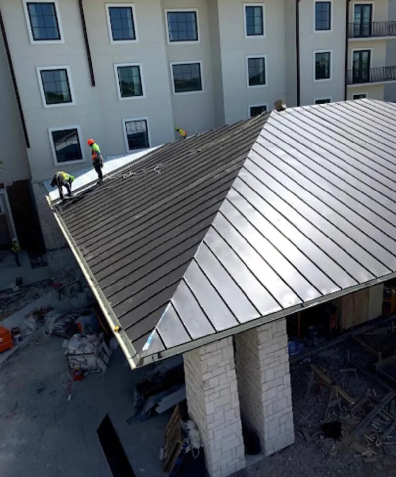 Crew installing standing seam metal roof panels on a commercial project in Sycamore